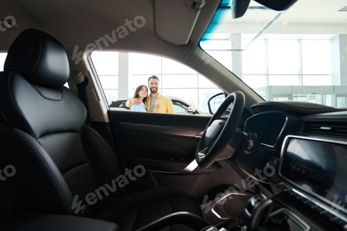 Preview: Happy woman and man looking at camera in car center
