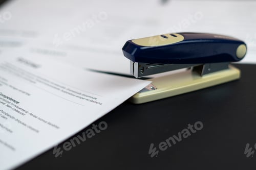 Preview: a stapler and the documents files in office on the table, staple the paper sheets of resume and cont