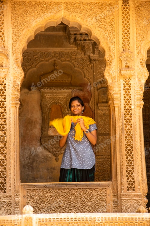 Preview: Young woman tourist in stone carved window, India.