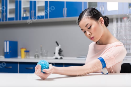 Preview: asian woman preparing for blood test by flexing rubber ball