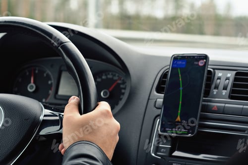 Preview: Driver's hand on steering wheel with navigation app on smartphone, illustrating modern travel