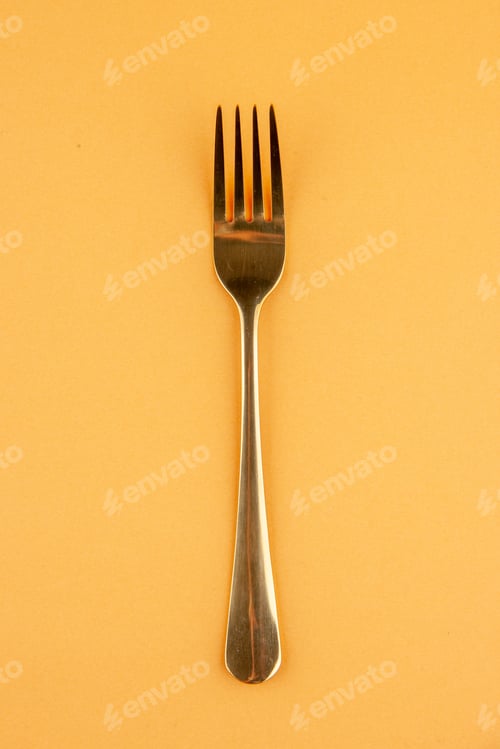Preview: Top view of elegant shiny stainless fork on isolated golden background with free space
