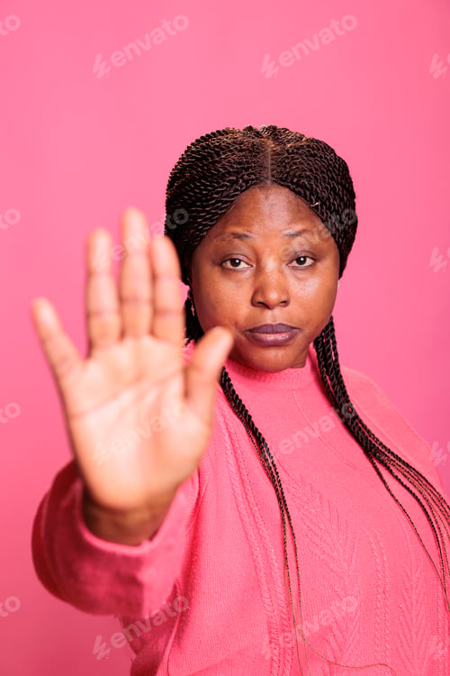 Preview: Irritated woman doing rejection gesture with hand in front of camera