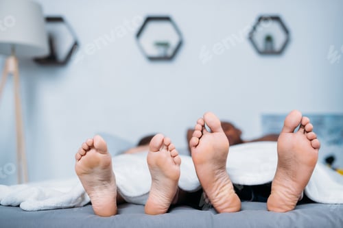 Preview: multicultural couple lying under blanket in bed