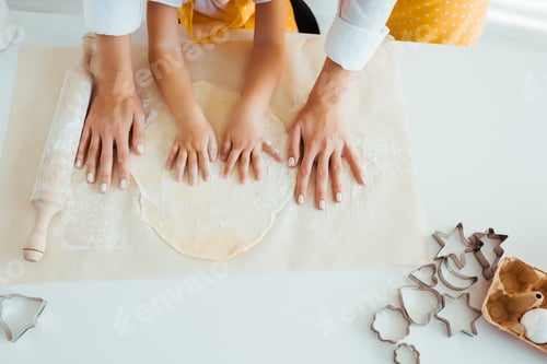 Preview: top view of mother and daughter with dough, rolling pin and dough molds on table