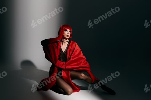Preview: Stunning Young Drag Queen Posing Elegantly in Bold Red Attire Under Dramatic Lighting