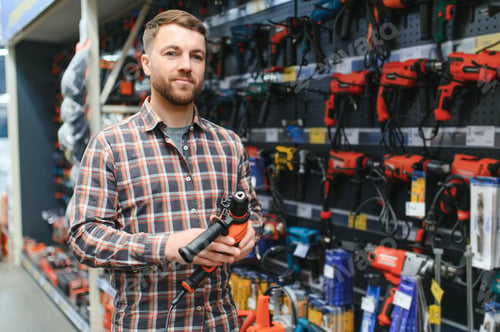 Preview: handsome young man shopping for tools at hardware store