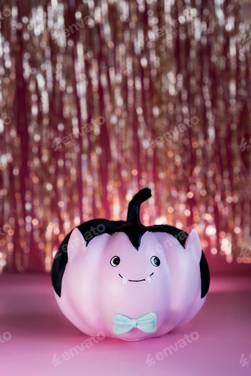 Preview: Funny and cute pink Vampire pumpkin with blue butterfly tie and golden tinsel curtain