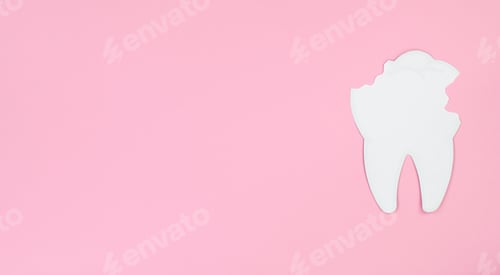Preview: White paper tooth with caries on a pink background, space for text