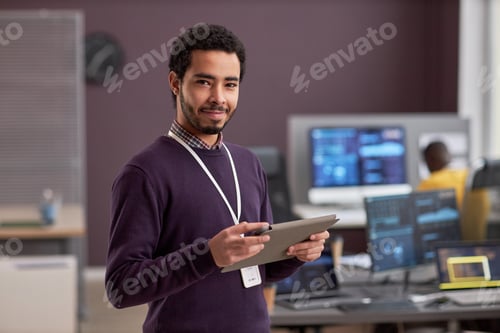 Vista previa: Retrato de cintura para arriba de un ingeniero de software sonriente que sostiene una tableta digital mientras está de pie en tecnología