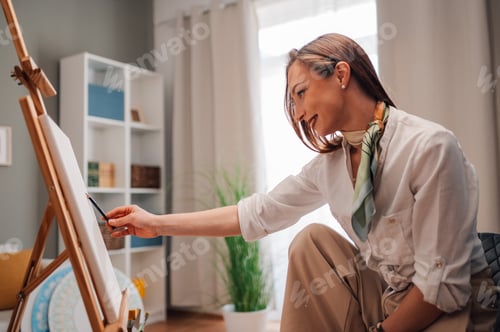 Preview: Female artist sketching on canvas in art studio at home