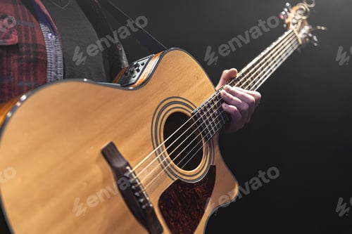 Preview: Guitarist playing acoustic guitar in the dark.