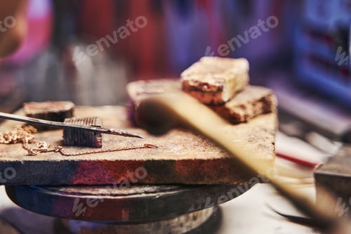 Preview: Golden chain lying on stone during soldering