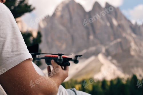 Preview: Cropped shot of man holding drone in front of mountain range