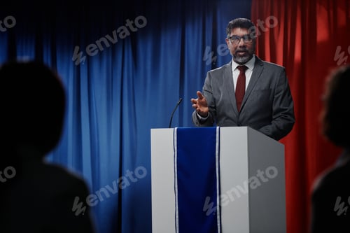 Man Speaks at Podium with Red and Blue