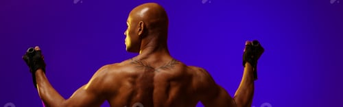 Preview: Back view of man performs exercises with expander on studio background. Strength and motivation
