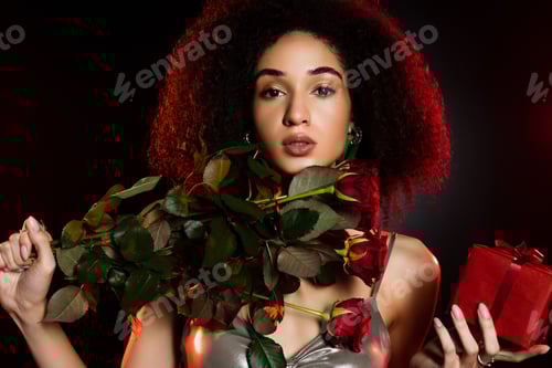 Preview: curly african american woman holding gift box and roses isolated on black