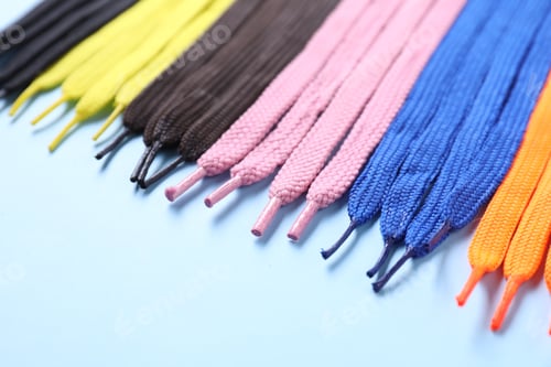 Preview: Many colorful shoe laces on light blue background, closeup
