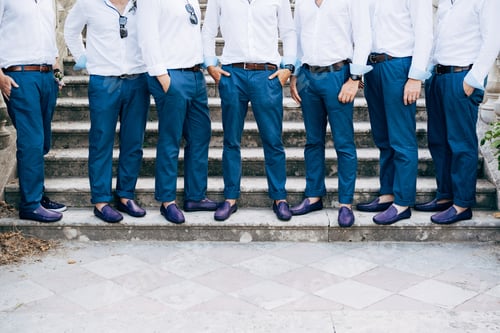 Preview: Seven groom's best men in identical blue trousers and shoes stand on the stairs, close-up