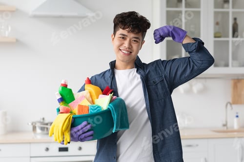 Preview: Positive asian guy with cleaning supplies showing muscles