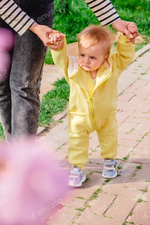Preview: a baby boy learns to walk holding his mother's hands