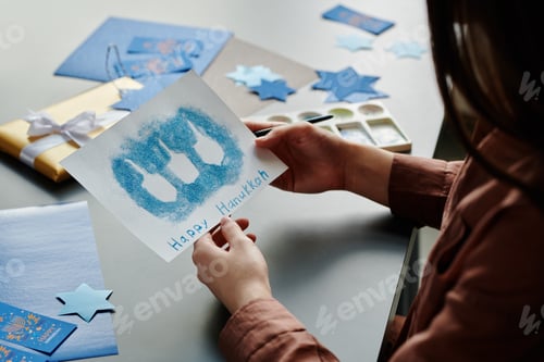 Preview: Unrecognizable brunette girl holding handmade Hanukkah postcard