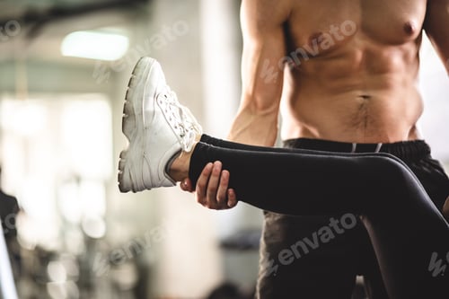 Preview: Personal trainer coach helping young woman exercising in sport gym, training for active