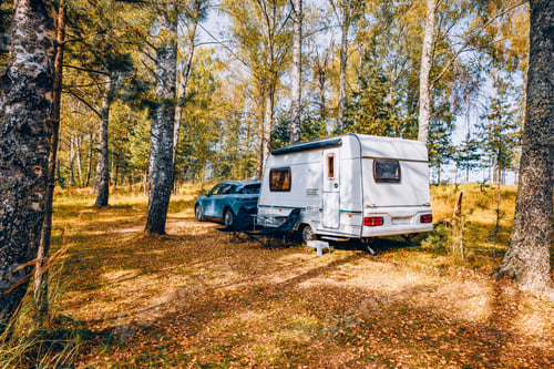 Preview: Camping caravan rv in autumn fall landscape. Caravan trailer in a golden tree forest.