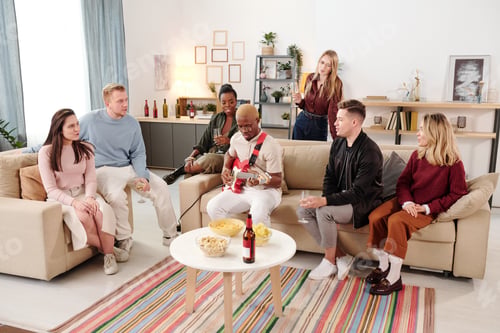Preview: Group of young intercultural friends listening to African guy singing at party