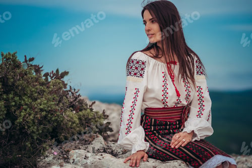 Preview: Atractive woman in traditional romanian costume on mountain green blurred background