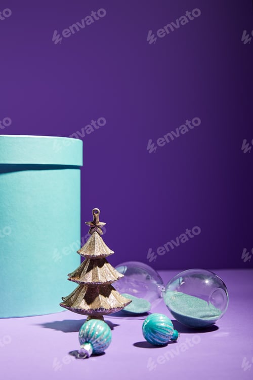 Preview: blue gift box and decorative Christmas tree with baubles and hourglass on purple background