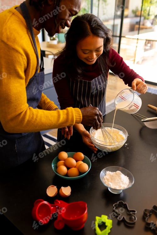 Preview: Happy diverse couple baking christmas cookies mixing dough in kitchen, copy space