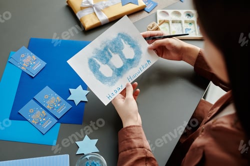 Preview: High angle of hands of young woman holding Hanukkah greeting card
