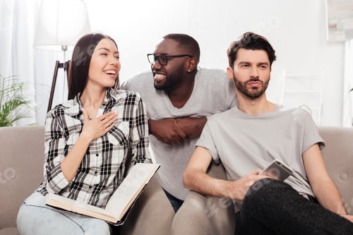 Preview: Young friends sitting on sofa cheerfully discussing something