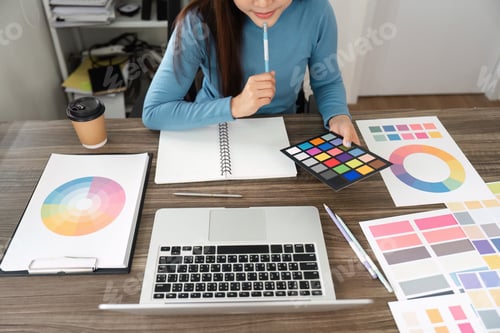 Preview: A design enthusiast engaged in color palette selection using color charts.