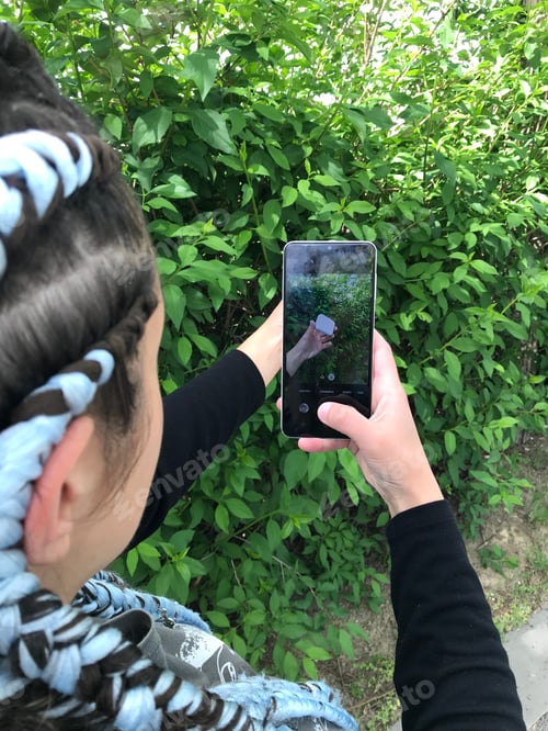 Preview: A girl with blue braids using white Smartphone. || Outdoors || Natural light || Outside || Hand