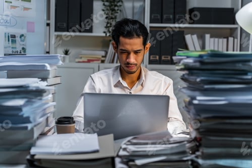 Preview: Frustrated Asian young businessman worker working on table in office.