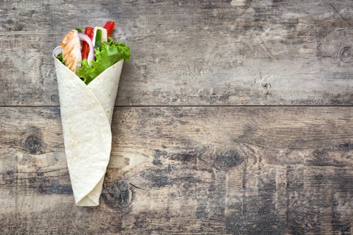 Preview: Chicken caesar salad wrap on rustic wooden table with copy space