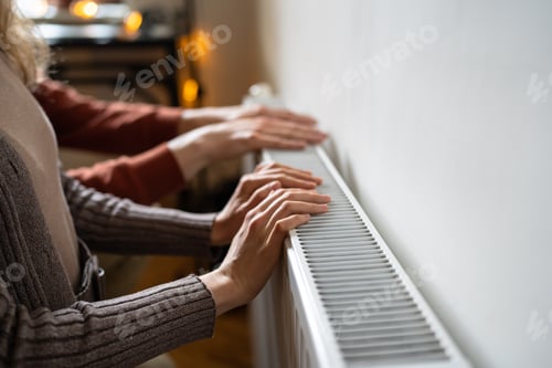 Preview: Family couple homeowners touching cold radiator with hands, preparing home for freezing temperatures