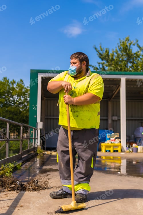 Preview: Worker in a recycling factory or clean point and garbage with a face mask