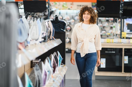 Preview: Woman choosing clothes iron in electronics store