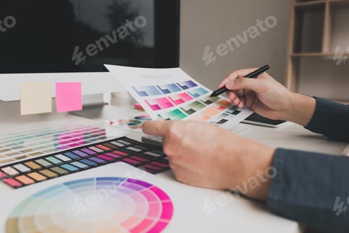 Preview: Hand designer choosing colors for doing graphic on laptop.