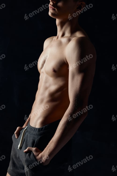 Preview: bodybuilder with a naked torso on a black background side view fitness