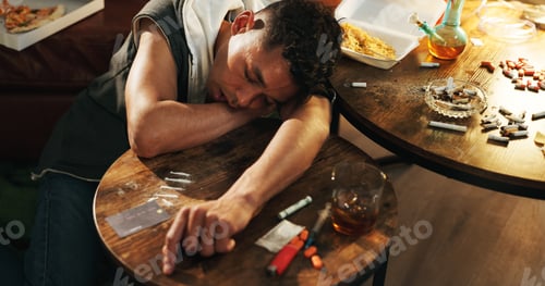 Preview: Drugs, overdose and man with face on table, health risk and narcotic danger in apartment at night.