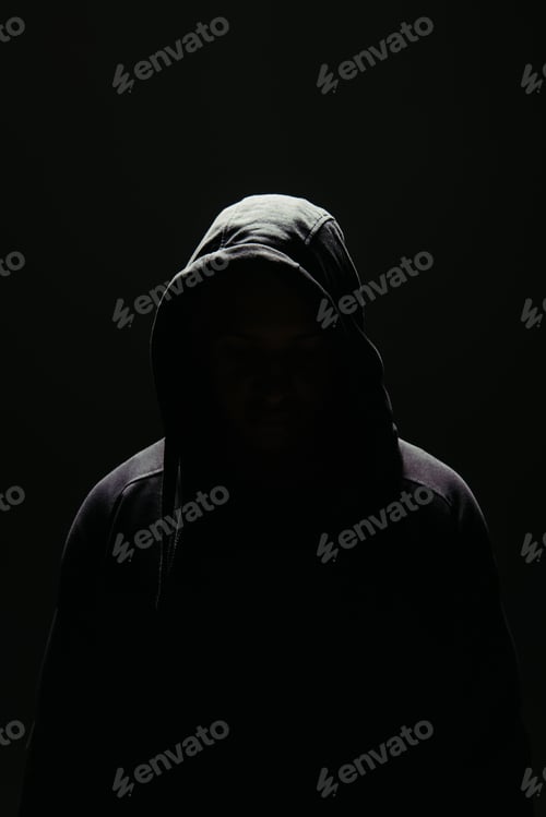 Preview: Silhouette of hooligan in hood standing in lighting isolated on black