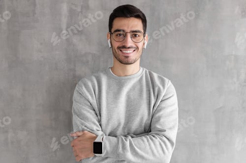 Preview: Portrait of smiling handsome man in sweatshirt and smart watches, standing with crossed arms