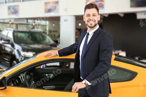 Preview: Young businessman standing near auto in salon. Buying new car
