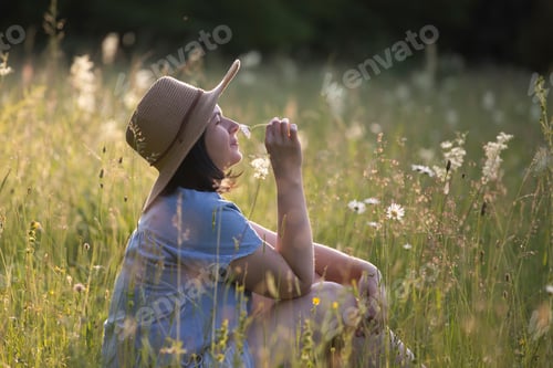 Preview: Trendy woman with stylish hat feeling free in the field with flowers