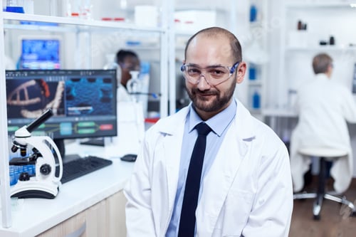 Preview: Pharmaceutical researcher sitting on stool looking at camera