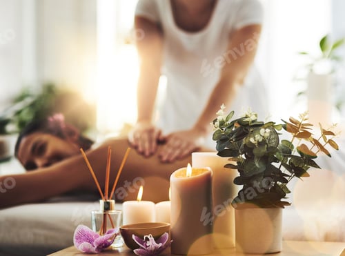Preview: Shot of spa essentials on a table with a woman getting a massage in the background